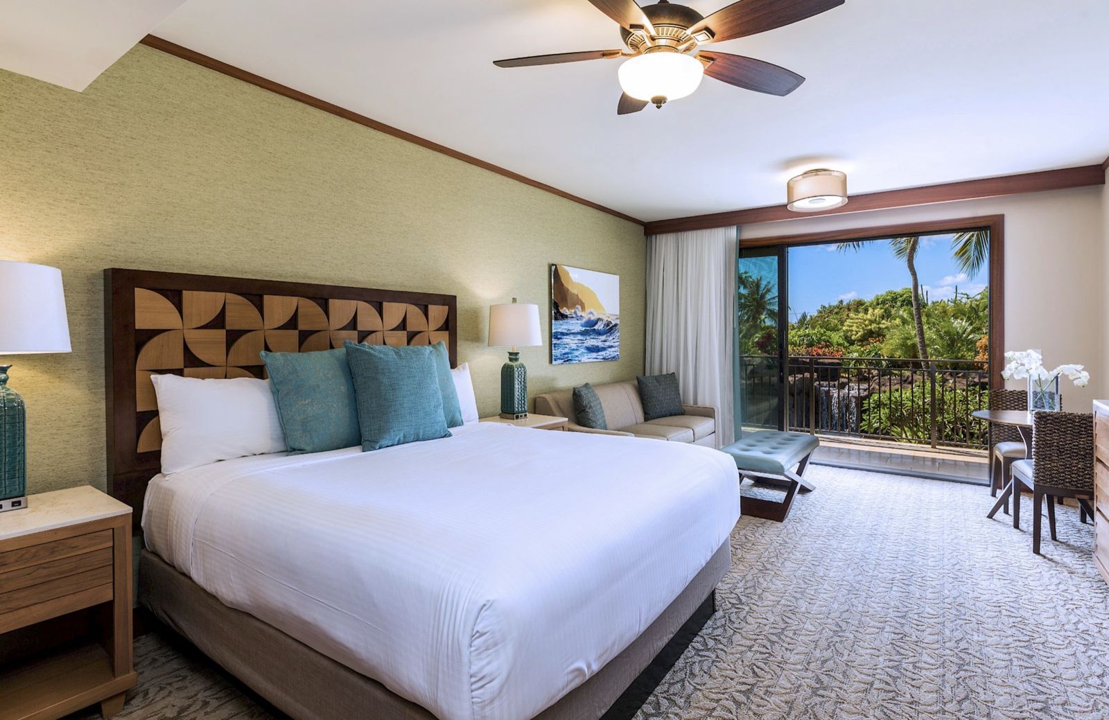 Bright guest room with a king bed, wood headboard, and doors opening onto a private lanai with garden views